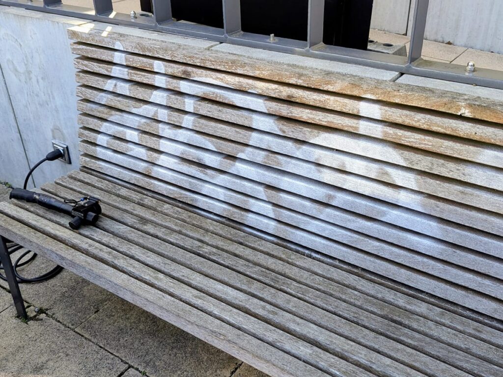 Beschmierte Holzbank mit Graffiti während der Laserreinigung