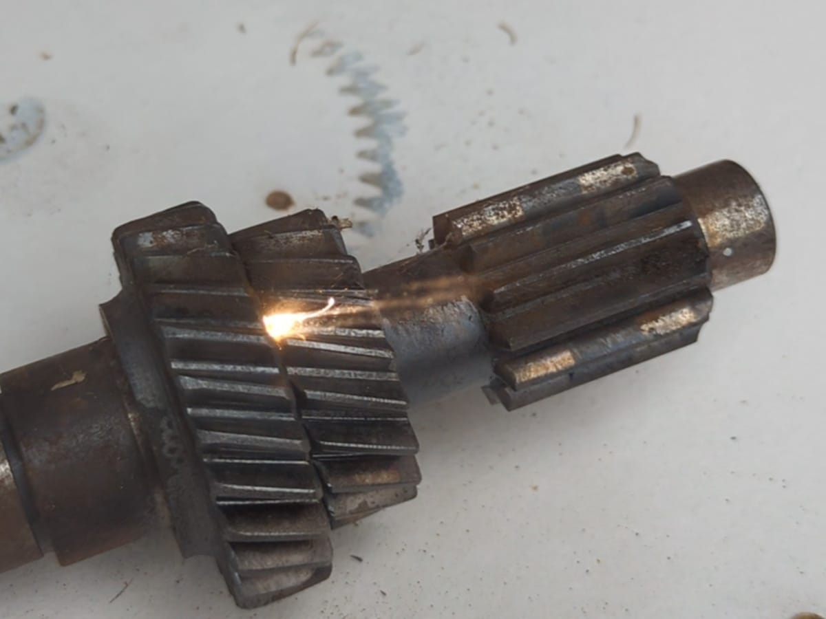 Verschmutzte Getriebewelle mit Zahnrädern während der Laserreinigung mit Rost und Ablagerungen