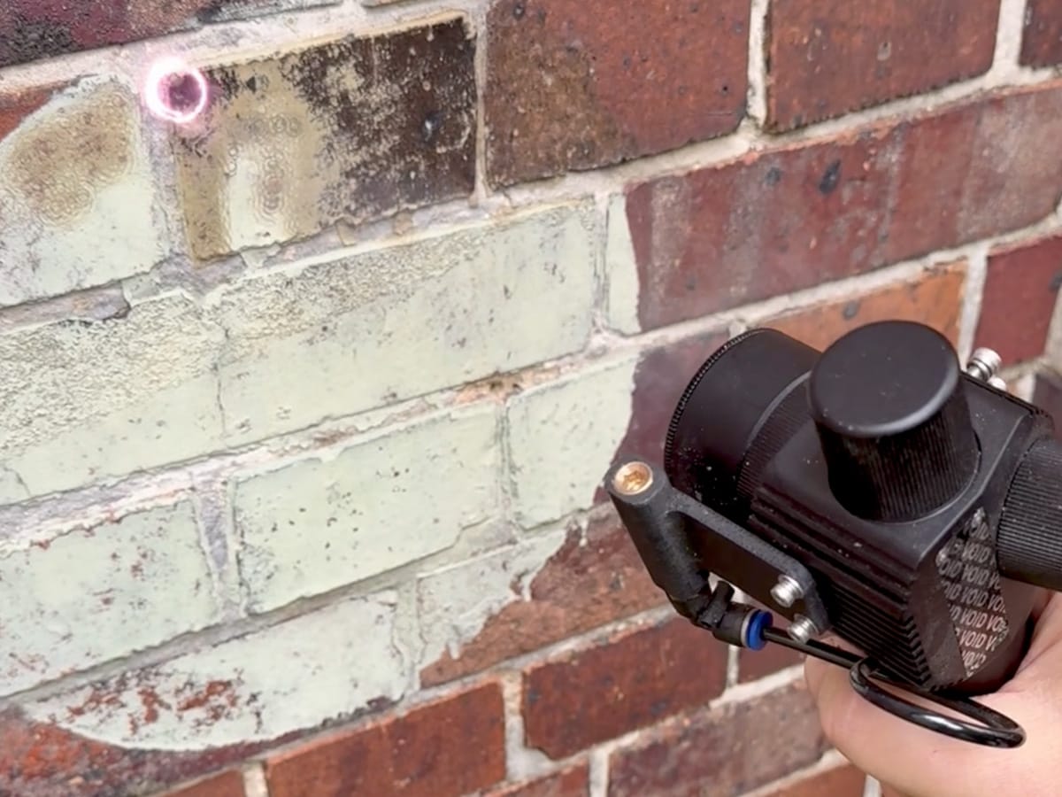 Laserreinigung einer bemalten Klinkerfassade während der Entfernung alter Farbschichten